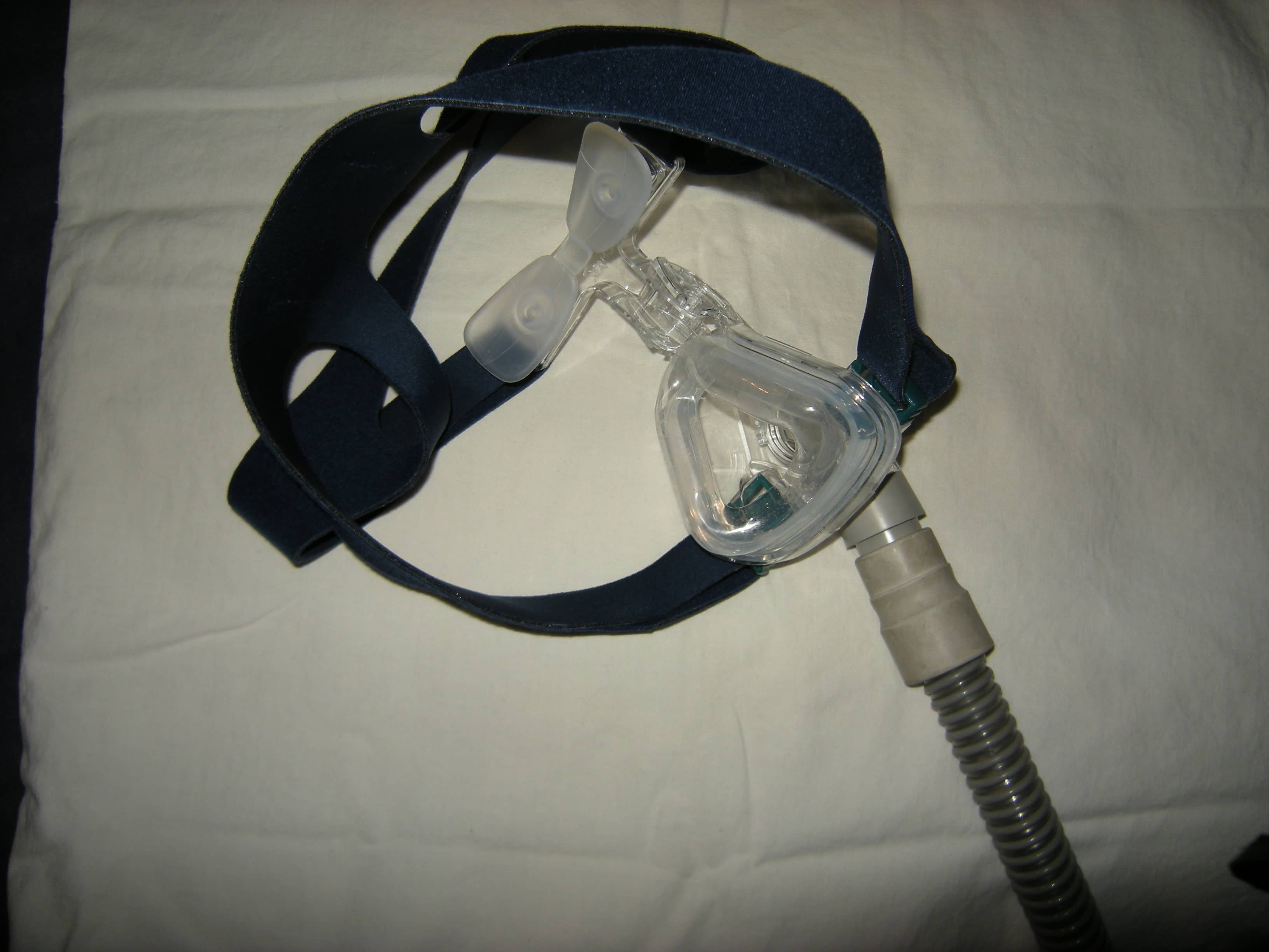 CPAP nasal mask and tubing placed on bedding.